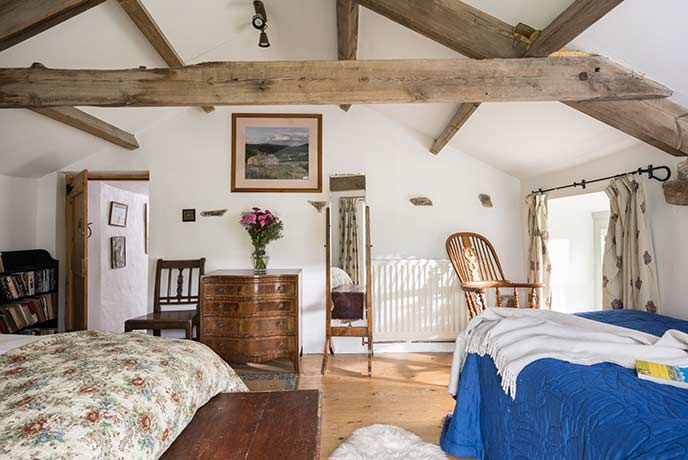 One of the charming bedrooms with wooden beams, vintage furniture, and floral decor