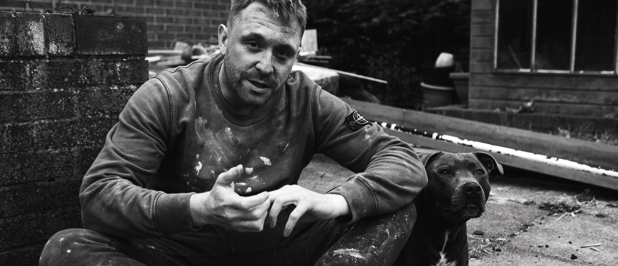 Black and white image of character, Danny, sat with a pit bull dog.