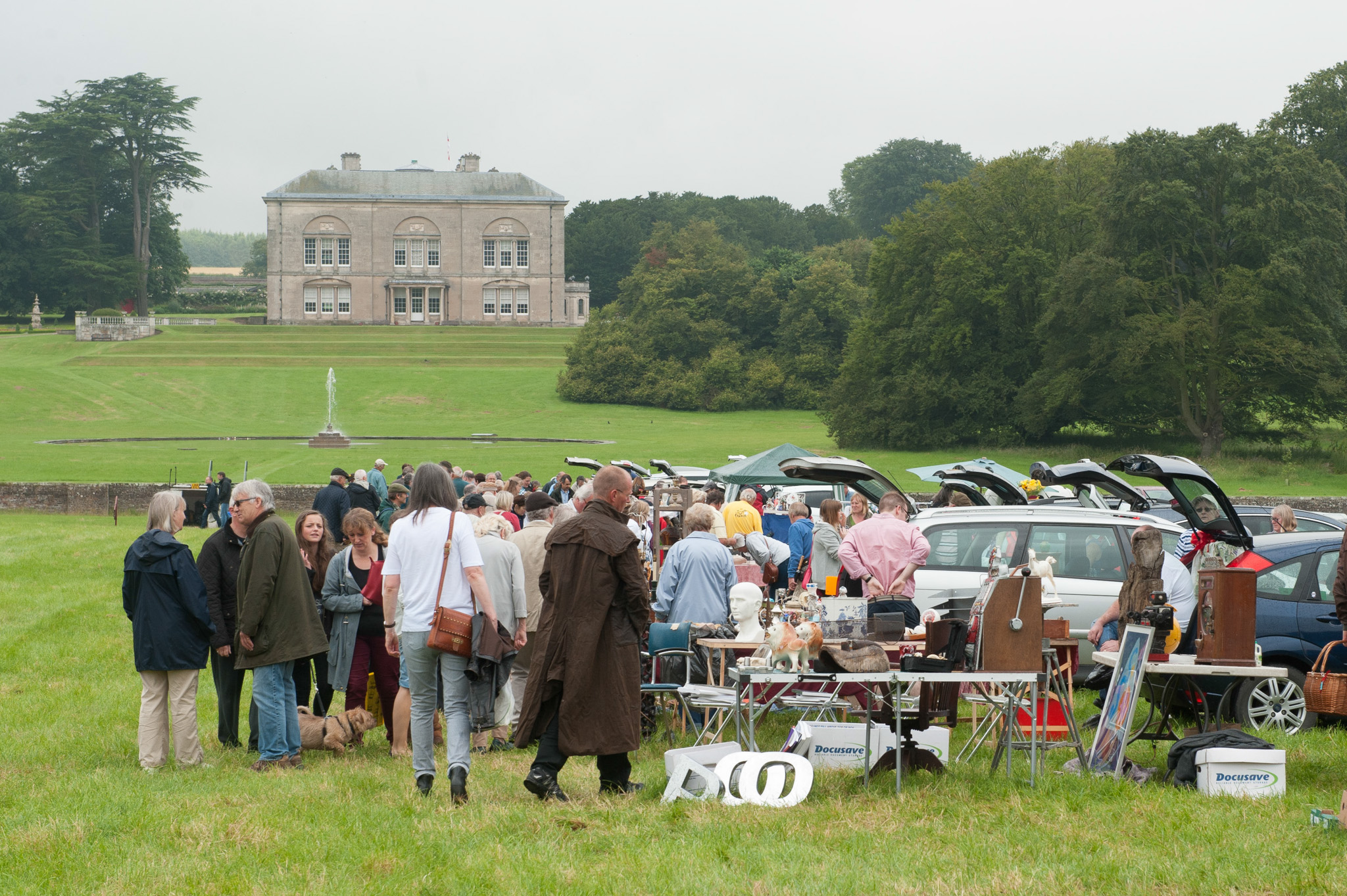 Lively outdoor car boot sale with people browsing stalls on a green field