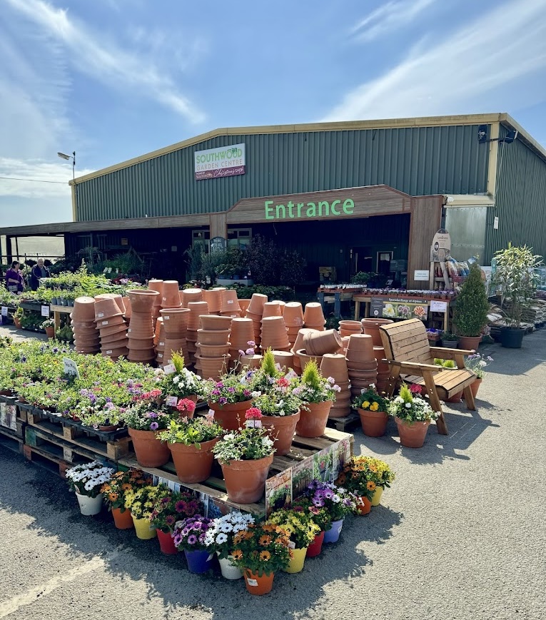 Entrance of garden centre with colorful flowers and terracotta pots displayed outside