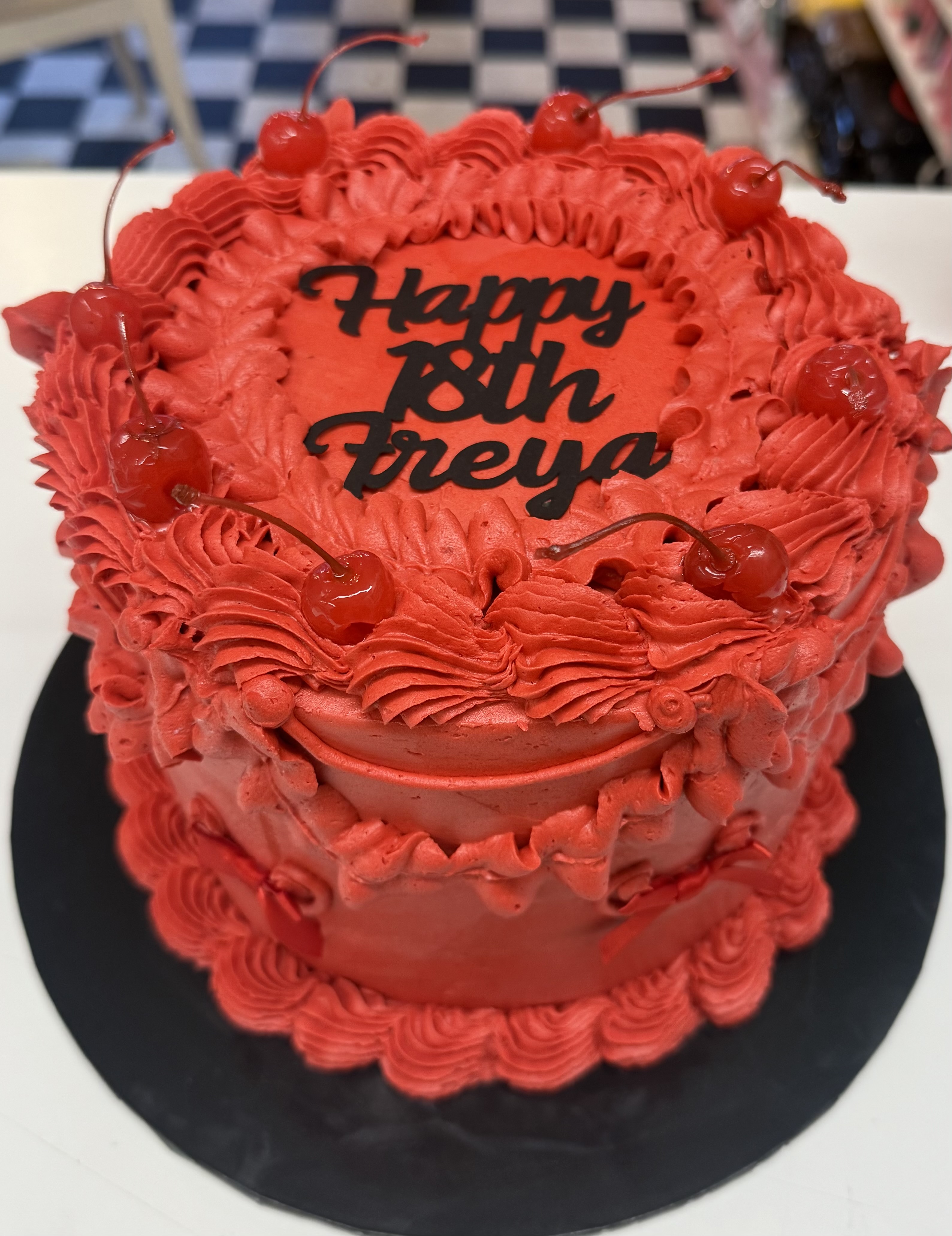 Vibrant red birthday cake with cherries and personalized icing