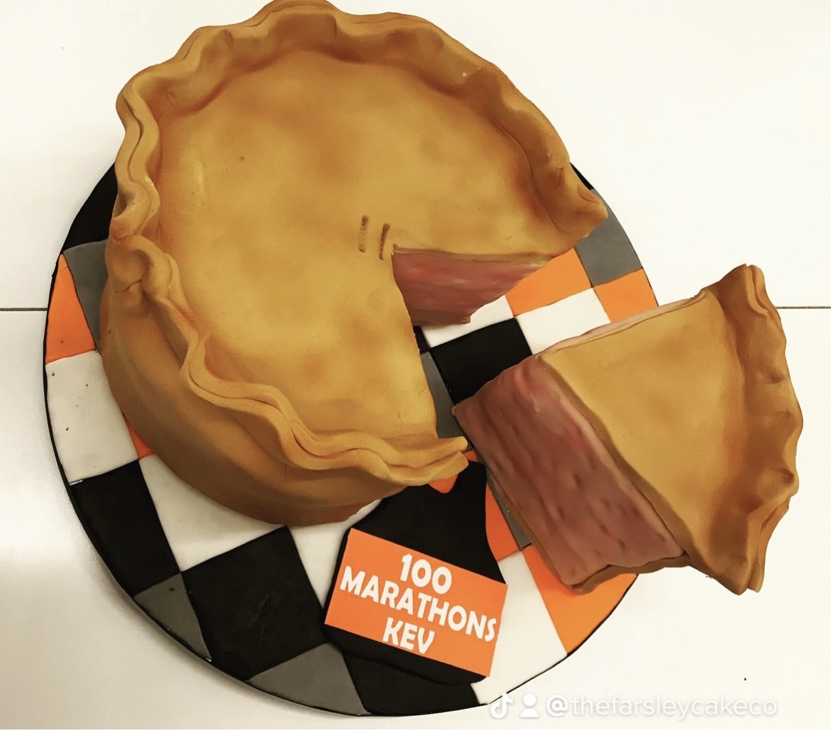 Realistic pie-themed cake with slice on checkered board