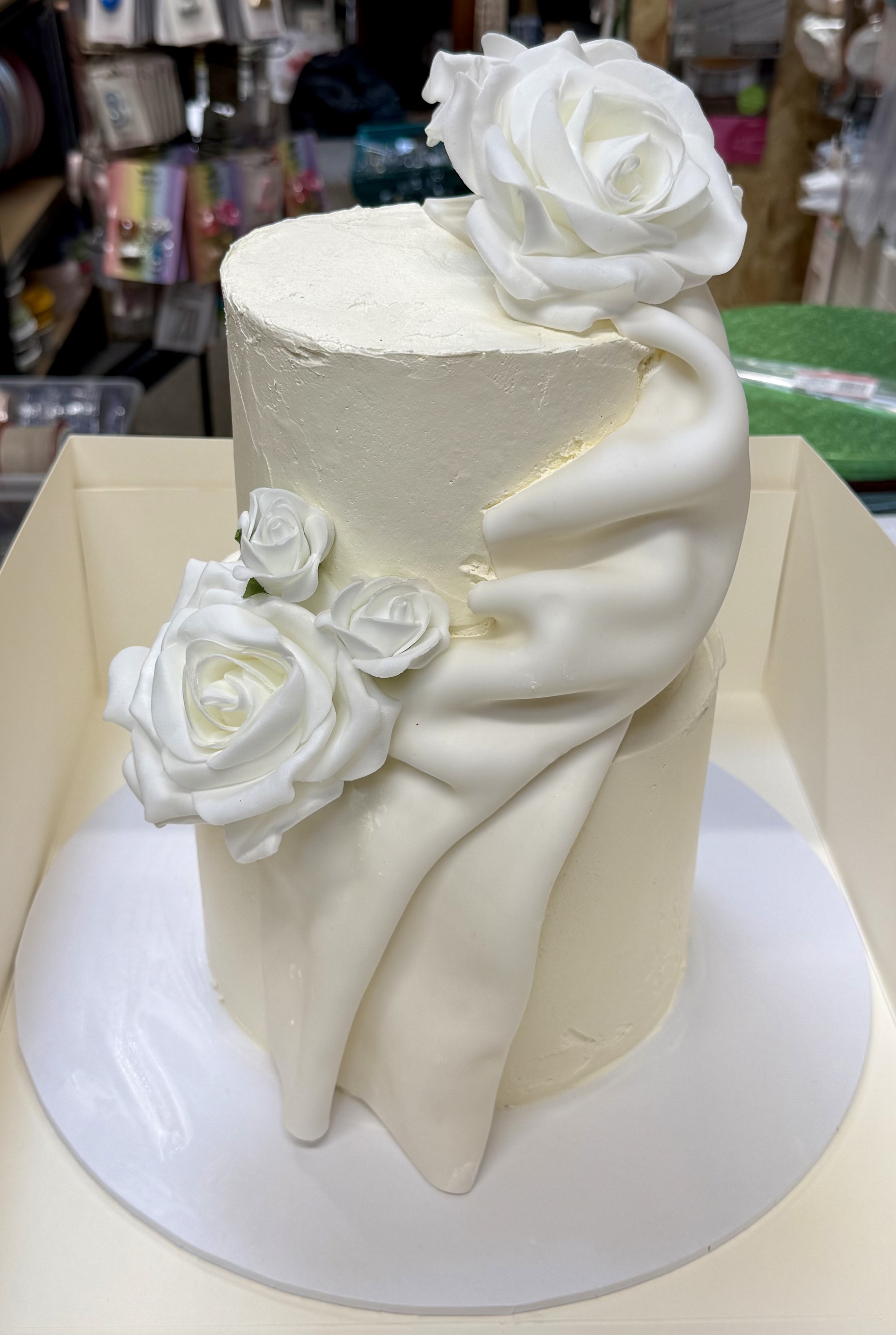 Elegant two-tier cake with white roses and draped fondant