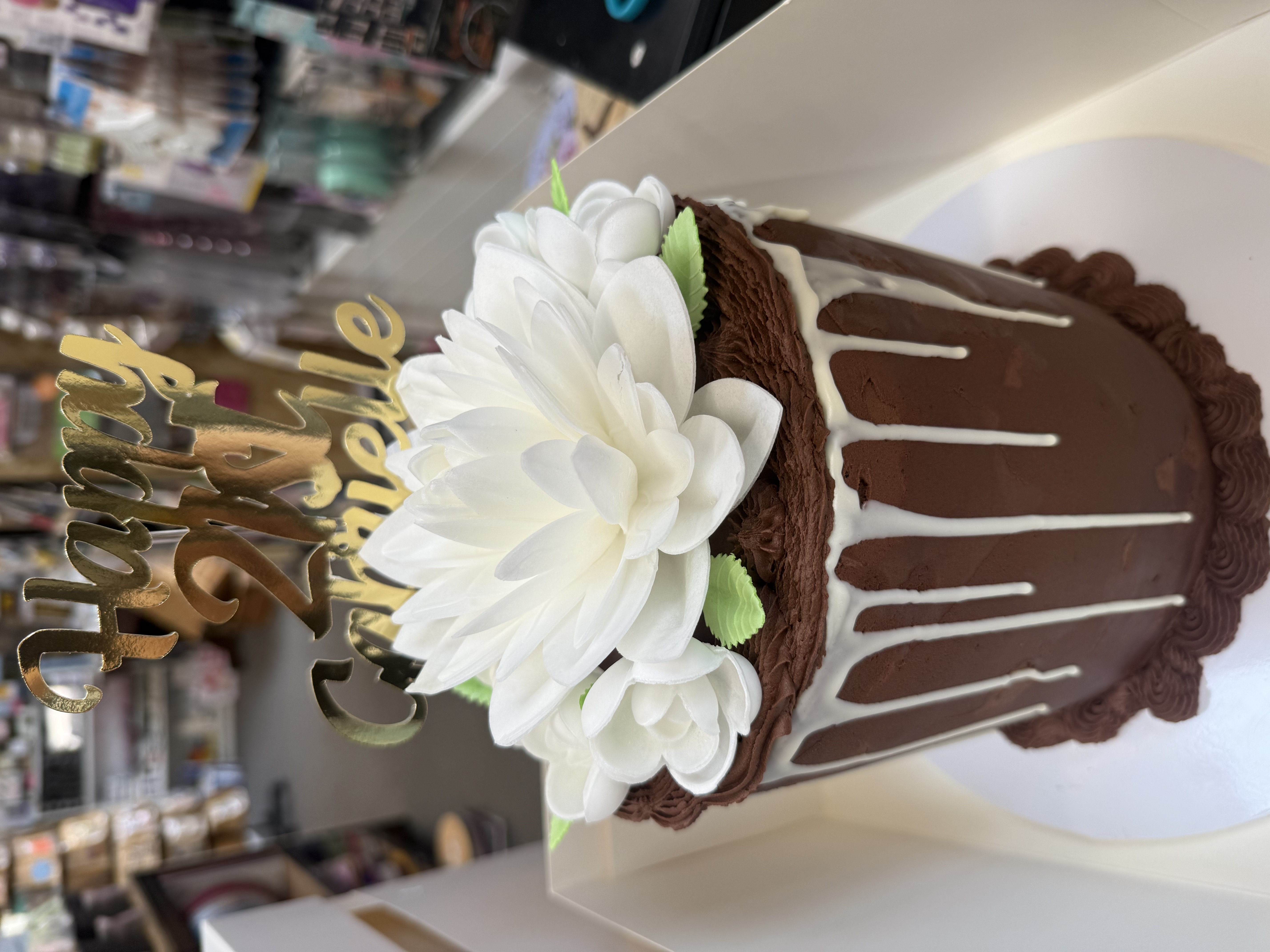 Chocolate cake with white flower decoration and gold 'Happy 21st' topper