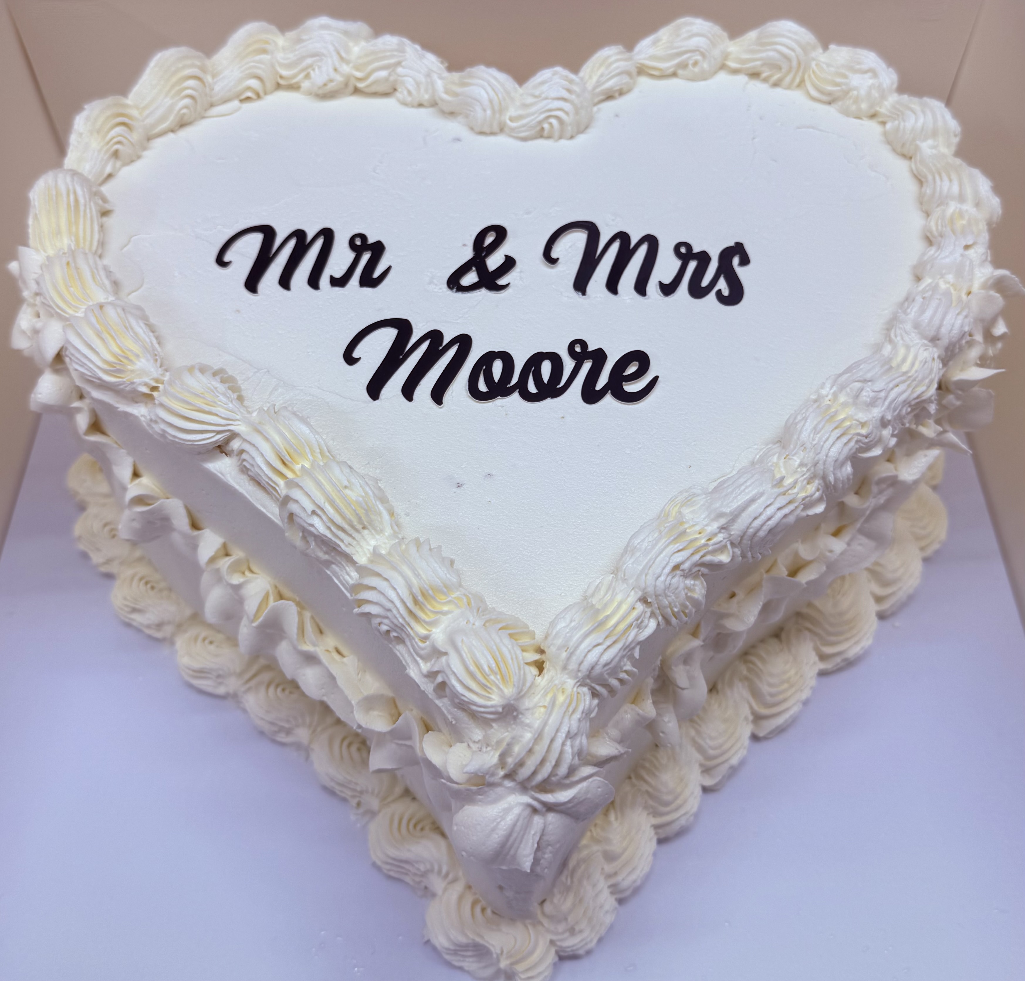 Heart-shaped wedding cake with white frosting and decorative piping