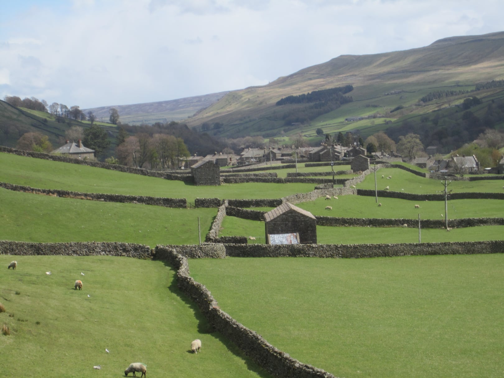 Scenic view of lush green fields with stone walls and distant hills