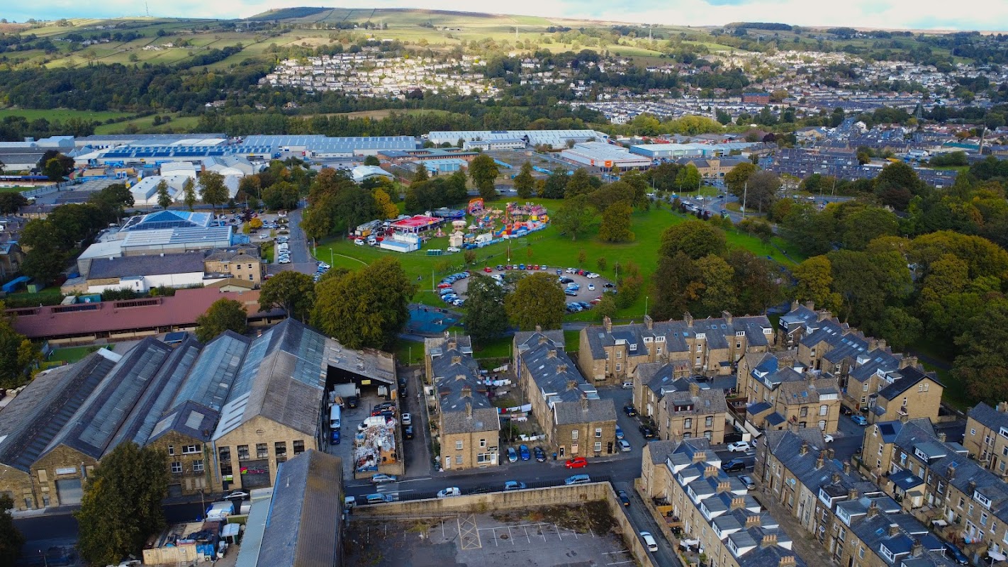 Aerial view of Victoria Park Car Park surrounded by buildings, greenery, and a colorful playground in Keighley, Yorkshire.
