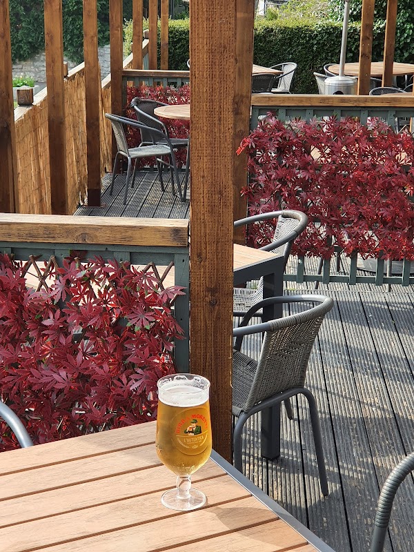 A glass of beer on a wooden table, surrounded by red foliage and outdoor seating at The White Horse restaurant.