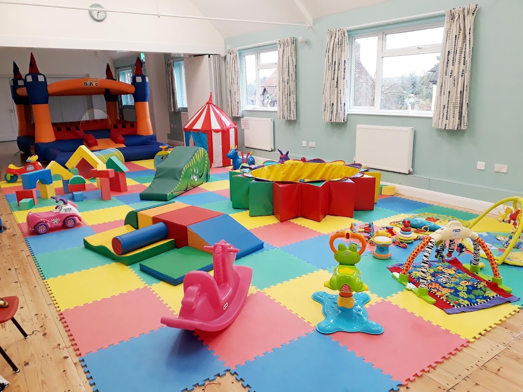 Brightly colored play area with a bouncy castle, soft toys, and various children’s play equipment on foam tiles.