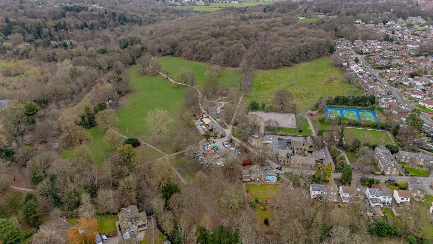 Aerial view of Meanwood Park Playground, surrounded by trees, fields, and nearby residential areas.