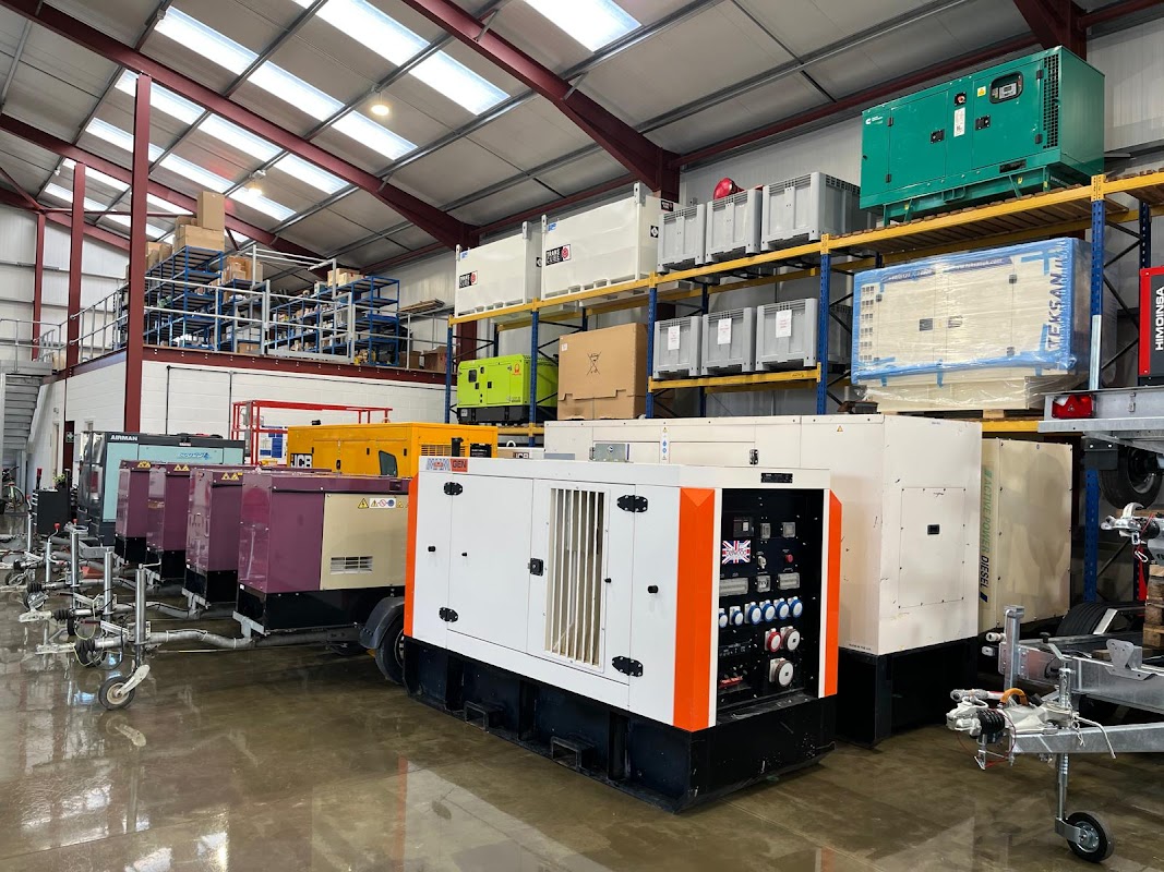 Industrial warehouse with various generators and equipment, stacked shelves, and a clean concrete floor.