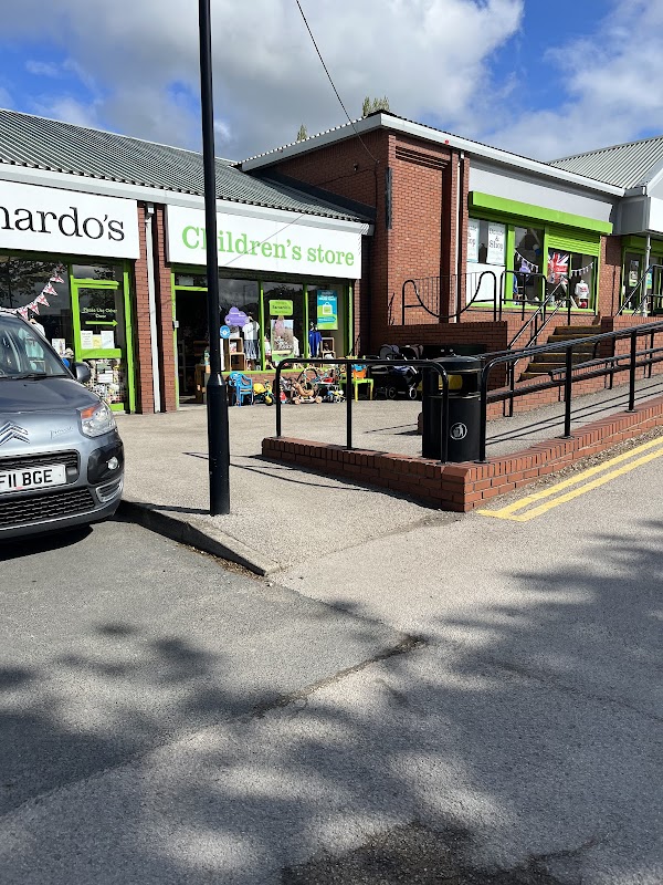 Barnardo's Children's Store with green signage, toys outside, and a ramp, set in a sunny Yorkshire street.