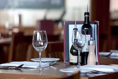Elegant dining setup at Piccolino Leeds with wine bottles, glasses, and neatly arranged cutlery on wooden tables.