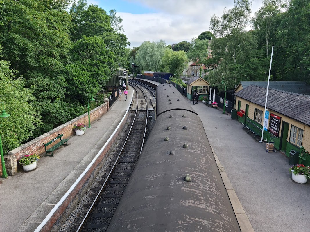 North Yorkshire Moors Railway car park with tracks, greenery, and historic station buildings in Pickering, Yorkshire.