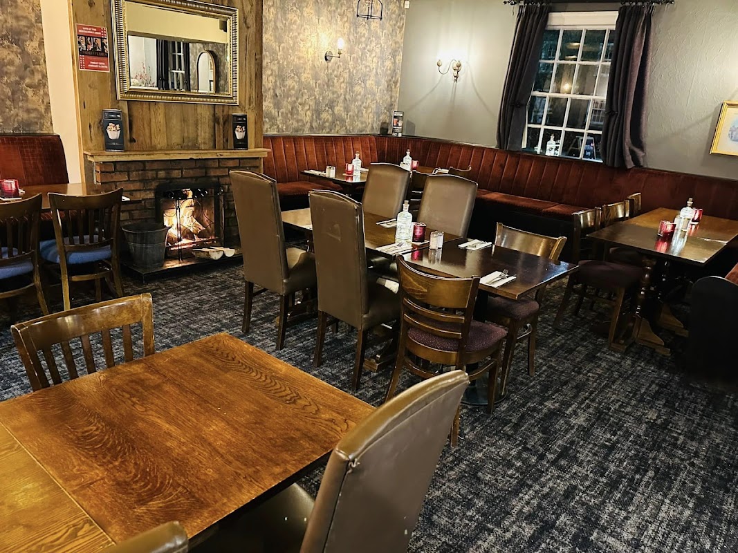 Cozy restaurant interior with wooden tables, leather chairs, a fireplace, and warm lighting in Shipton-by-Beningbrough.