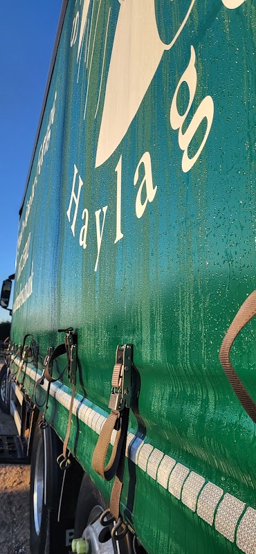 Green truck side with "Skerne Leys Haylage" logo and dew droplets, set against a clear blue sky.