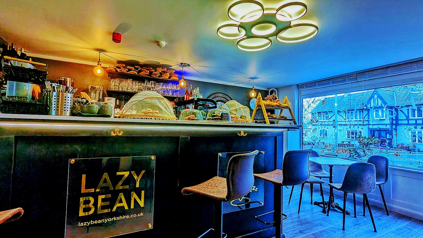 Cozy café interior with a sleek bar, illuminated display of pastries, and modern lighting, overlooking a quaint street.