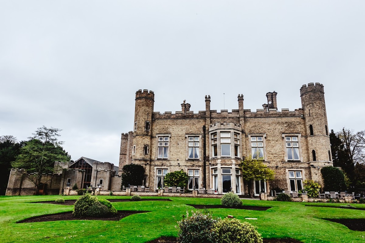 Historic stone castle with turrets, manicured lawns, and lush greenery in South Cave, Yorkshire.