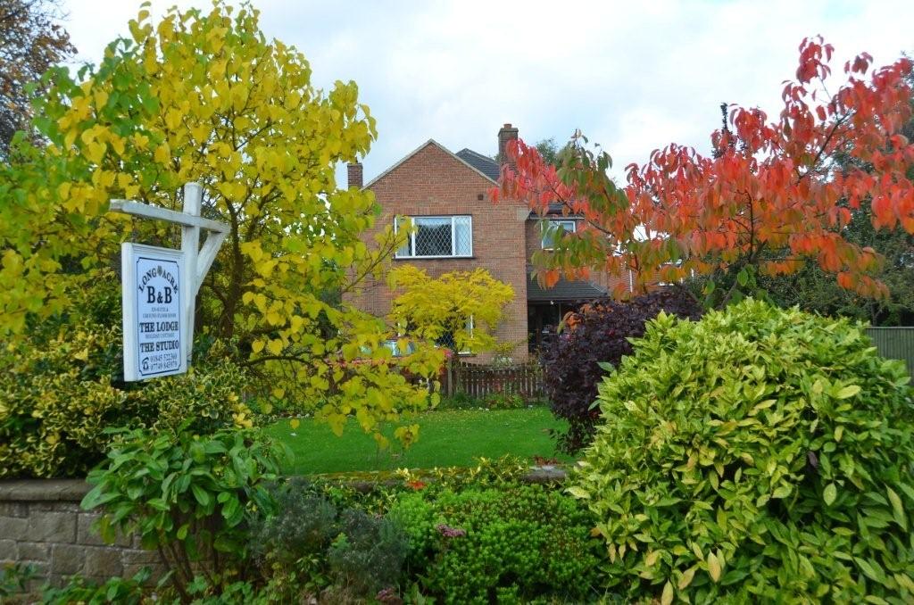 Long Acre Self-Catering Apartments surrounded by colorful autumn foliage and a lush garden in Sowerby, North Yorkshire.