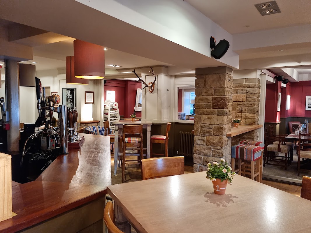 Cozy bar interior featuring wooden furniture, stone accents, and colorful seating in a warm, inviting atmosphere.
