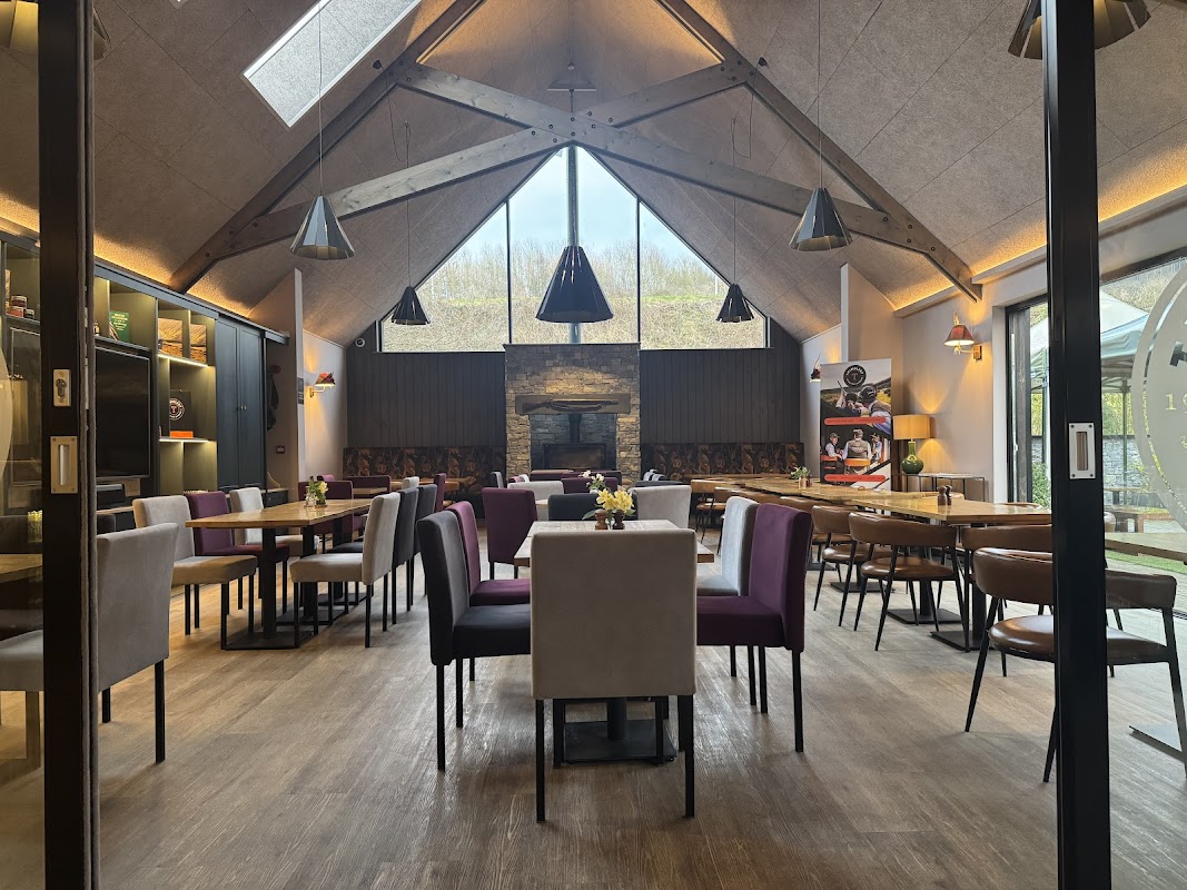 Modern interior of Thimbleby Shooting Ground with wooden beams, a stone fireplace, and various dining tables and chairs.