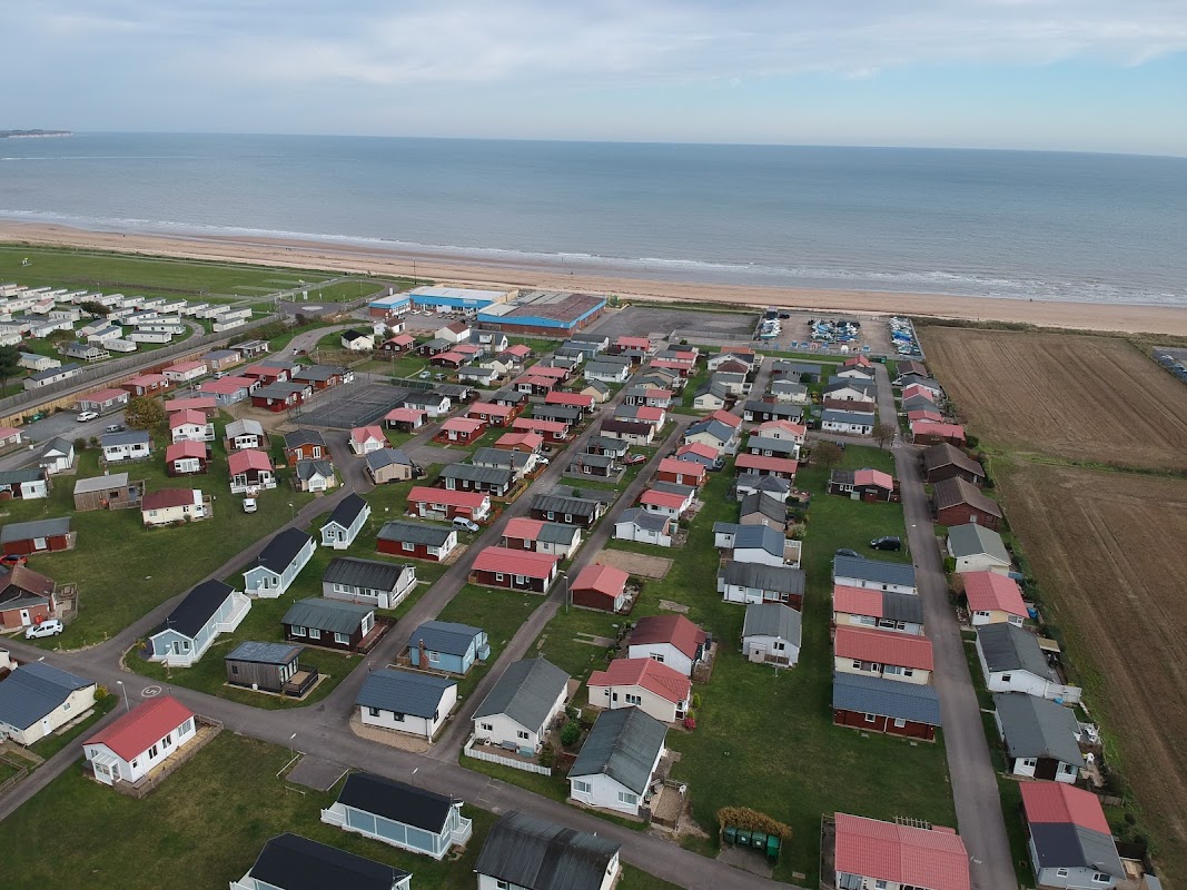 Aerial view of South Shore Holiday Village, featuring colorful chalets near the beach and a vast sea in the background.