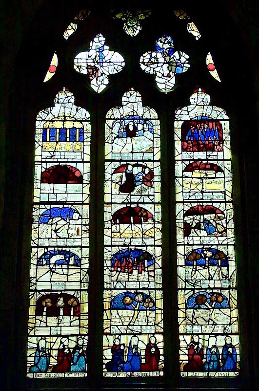 Stained glass window depicting biblical scenes with vibrant colors and intricate designs in a historic church setting.