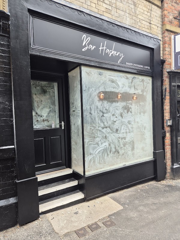 Signage reading "Bar Hashery" above a bakery entrance with large glass windows and decorative lighting.