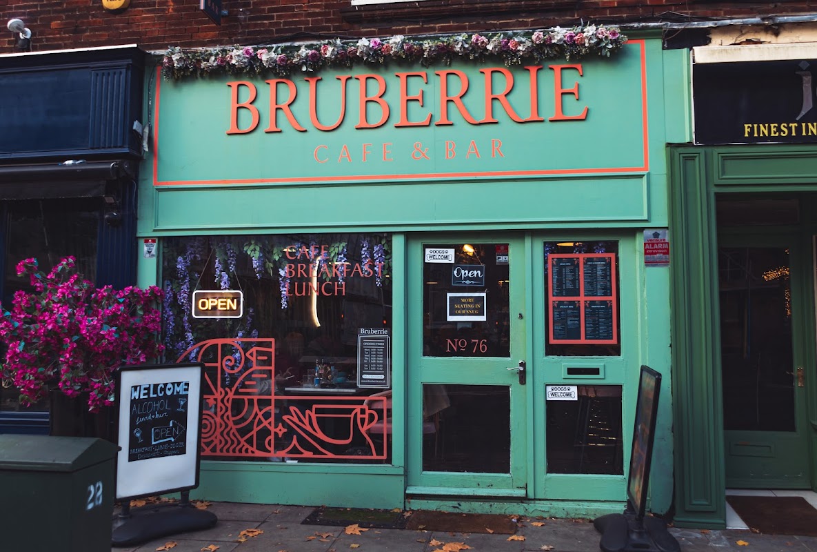Brightly colored café facade with "Bruberrie Café & Bar" sign, outdoor seating, and floral decorations.
