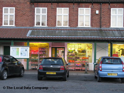 Corner shop with colorful displays, parked cars in front, and large windows showcasing various products in York.
