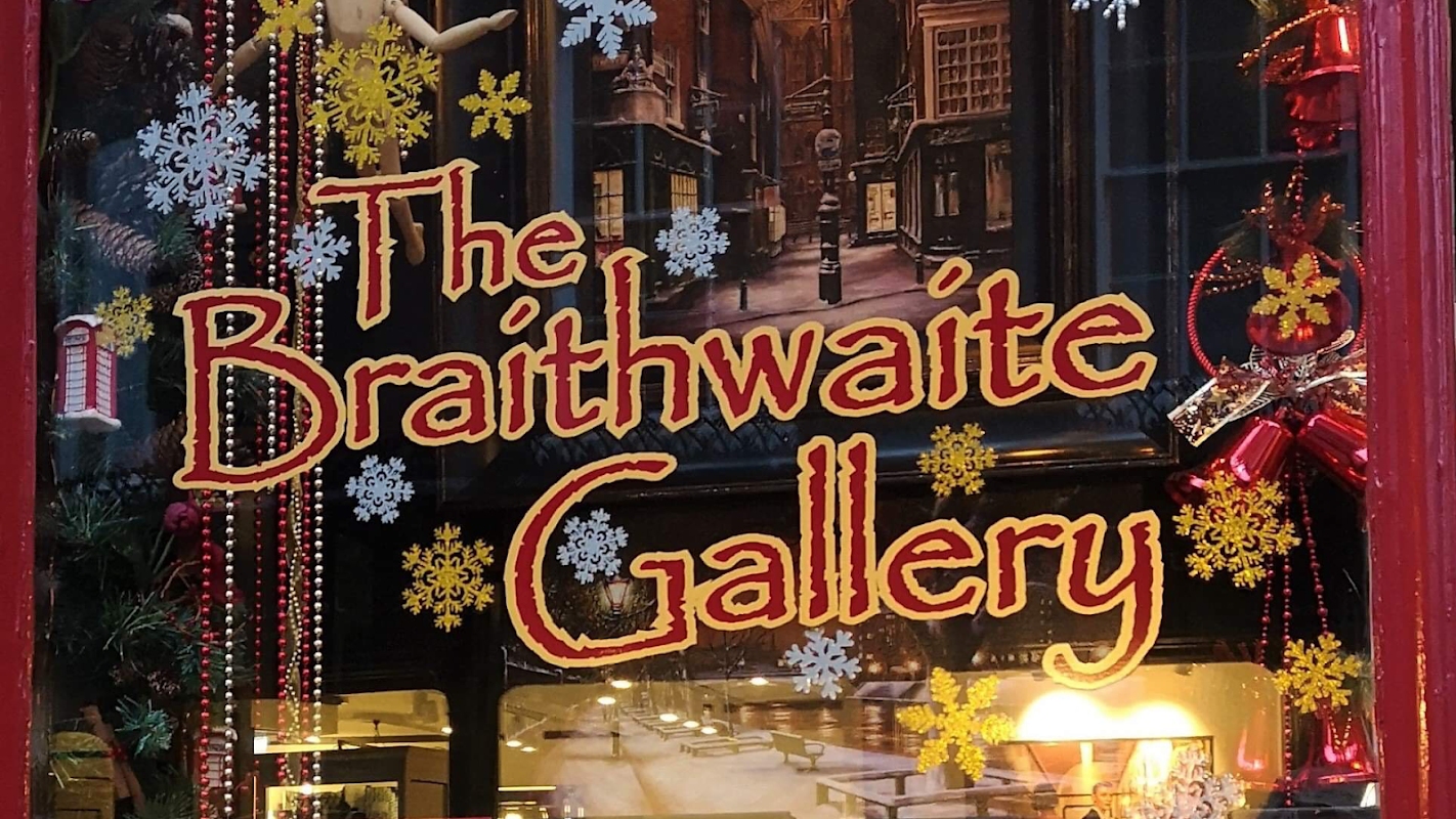 The Braithwaite Gallery sign adorned with festive decorations and snowflake designs in a charming storefront.