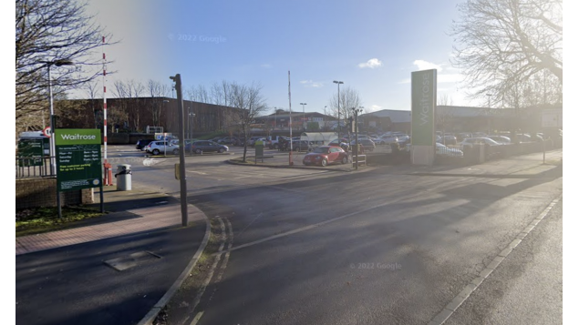 Car park entrance with signage for Waitrose, vehicles parked, and trees lining the area in York, Yorkshire.