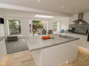 Modern kitchen and dining area in Abbey View cottage, Whitby, featuring white cabinetry and large windows.