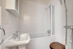 White-tiled bathroom with a classic sink, bathtub, and chrome fixtures in Pannett View apartments, Whitby.
