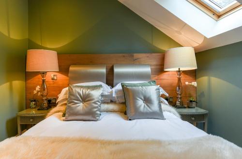 Cozy bedroom in Discovery Cottage, Whitby: plush bed with silver pillows, warm lighting, green walls, and skylight.