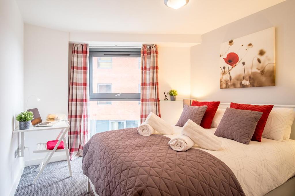 Stylish bedroom in Sheffield apartment, featuring a double bed, plaid curtains, wall art, and a desk with a laptop.
