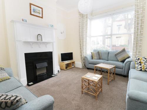 Cozy living room in Seaside Villa, Bridlington, featuring blue sofas, a fireplace, and large window with natural light.