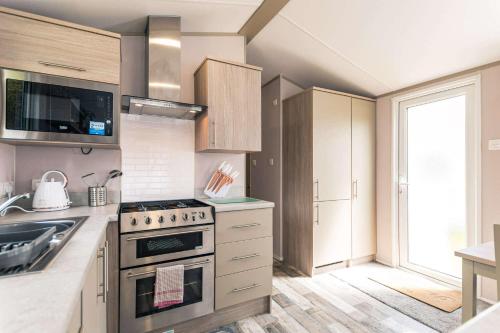 Modern kitchen with stainless steel appliances, light wood cabinets, and bright natural light in Yew Tree Lodge, Allerthorpe.