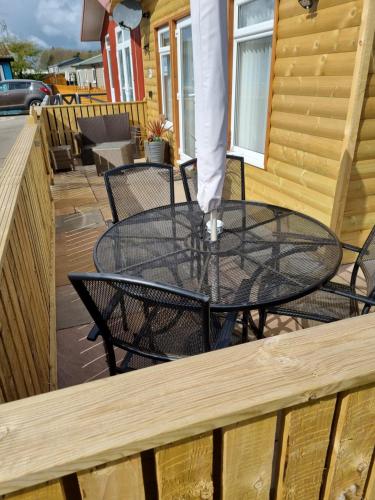 Chalet patio with round metal table, umbrella, wooden fencing, and log cabin exterior in Bridlington, Yorkshire.