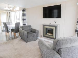 Modern hotel lounge at Beech 23, Scarborough, featuring grey sofas, wall-mounted TV, and dining area with striped curtains.