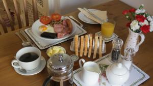 Full English breakfast with tea, toast, and juice on a wooden table at Pear Tree House B&B, Pickering.