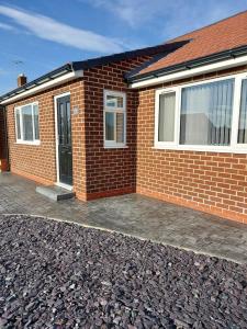 Brick bungalow with black door and large windows, surrounded by a stone path in Stockton on Tees, Yorkshire.