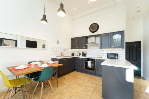Bright Leeds apartment kitchen with dark cabinets, dining table, colorful chairs, and modern lighting.