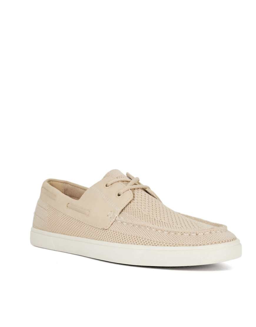 Cream-colored fabric boat shoes by Dune, featuring a breathable mesh design, lace-up front, and a white rubber sole for a stylish, casual look.