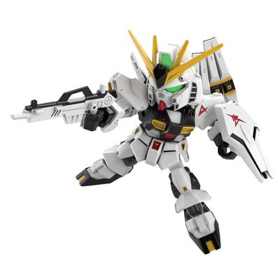 Nu Gundam SDEX model kit in white, black, and gold, featuring a green visor, yellow fin-like antennae, and armed with a rifle, posed dynamically.
