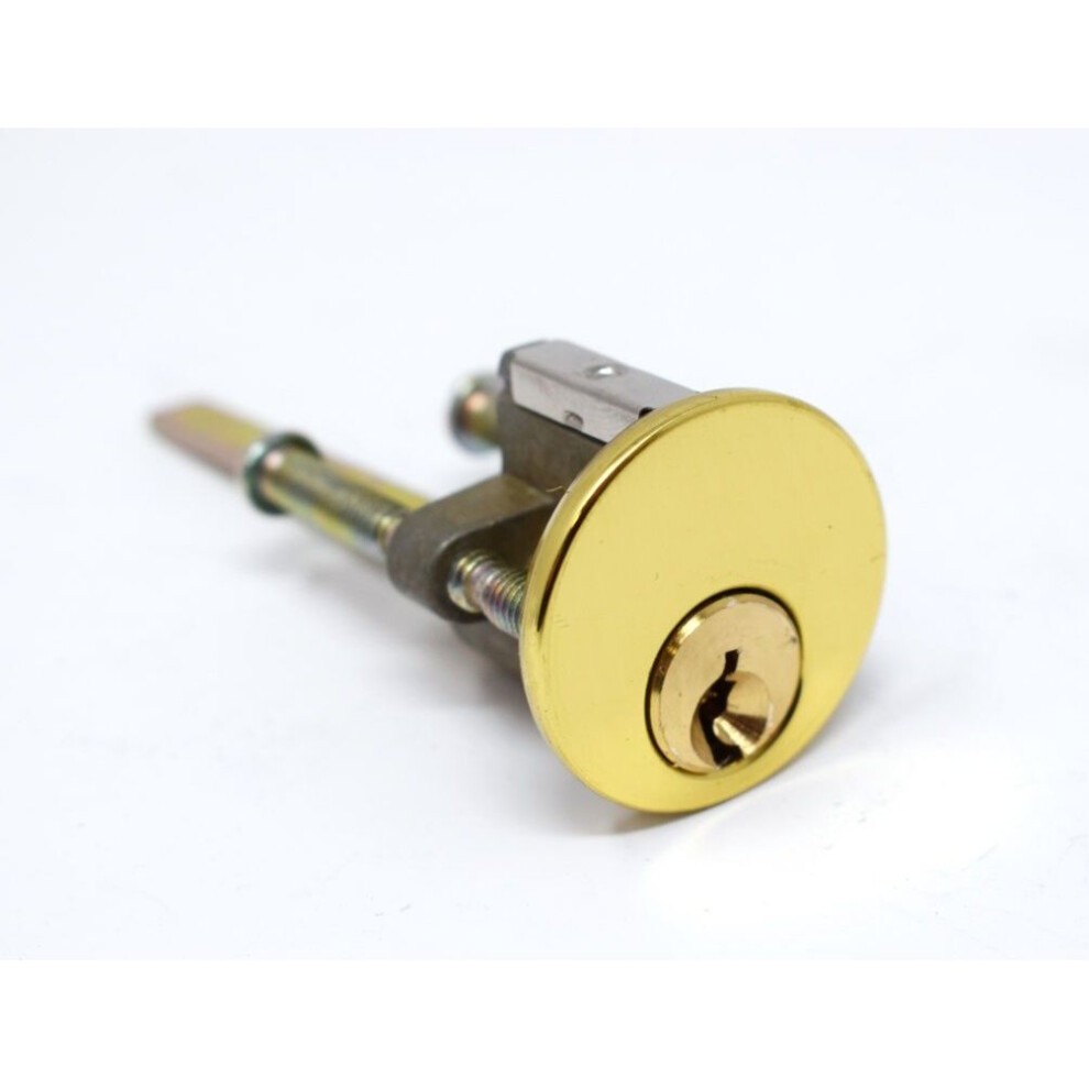 Brass rim cylinder lock featuring a shiny gold finish, a round faceplate, and a keyhole, with metal components for secure installation.