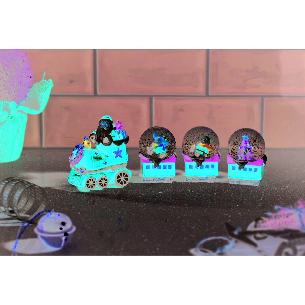 Colorful Santa's train decoration featuring a snow globe with a snowy scene, surrounded by smaller globes, all on a shiny surface with festive elements.