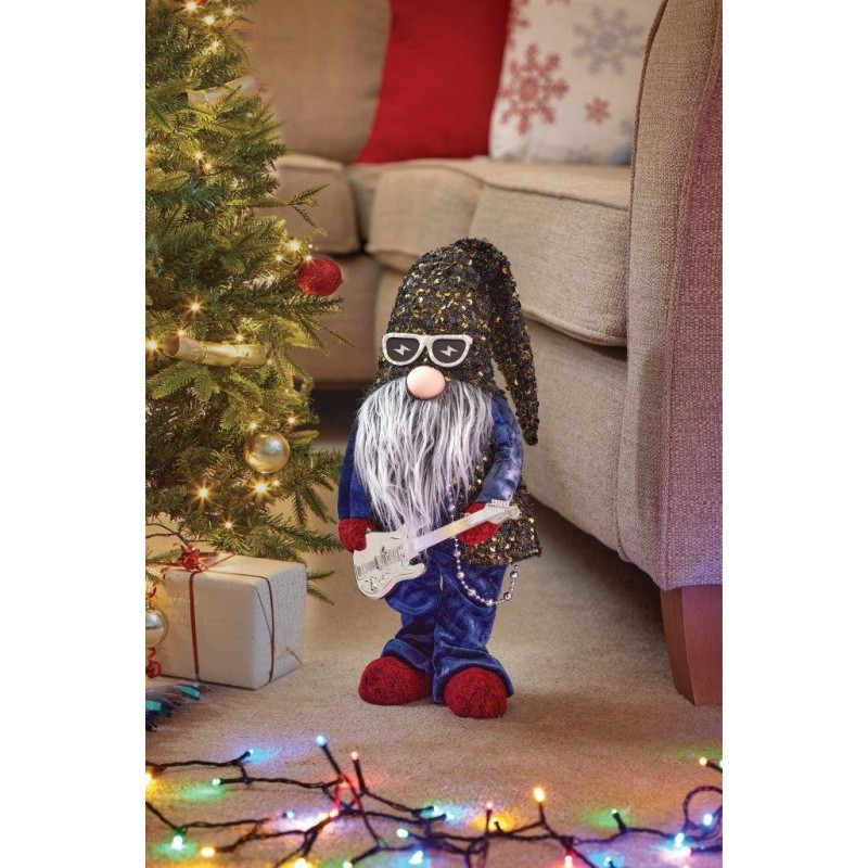 A 37cm plush garden gnome with a sparkly black hat, white beard, sunglasses, and blue outfit, holding a guitar, stands beside a Christmas tree adorned with lights.