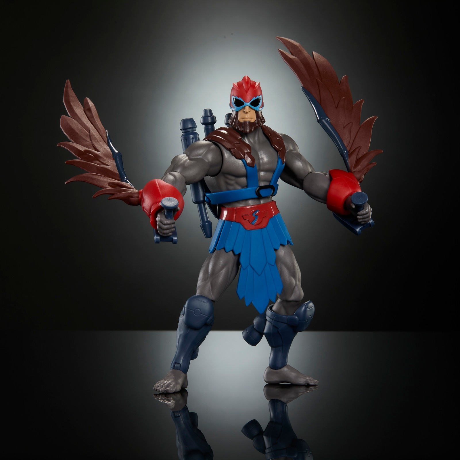 Stratos action figure features a muscular gray body, red and blue armor, feathered wings, and dual swords, standing against a dark, illuminated background.