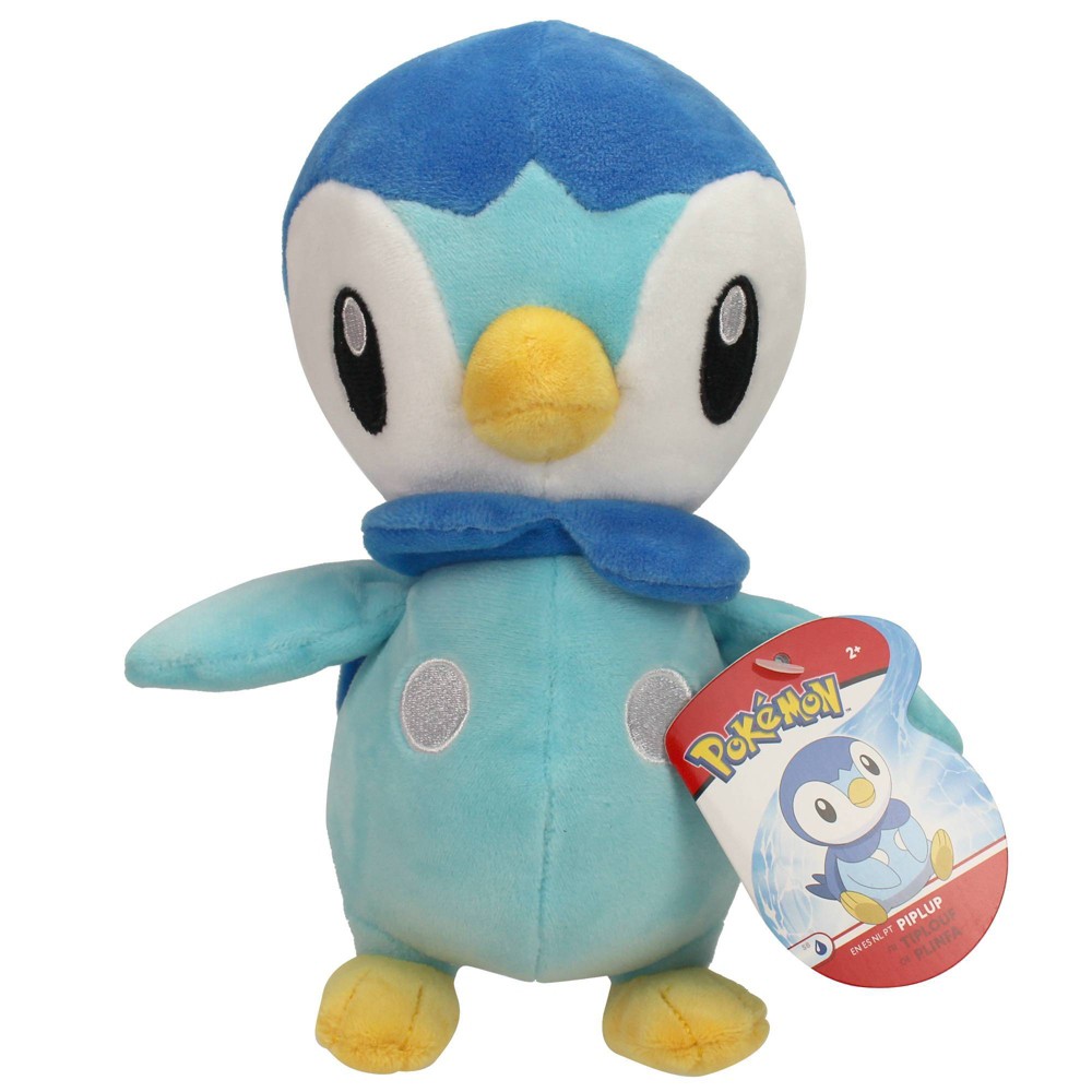 Blue and light blue plush Piplup soft toy with a round body, yellow beak, flipper-like wings, and a tag featuring the Pokémon logo.
